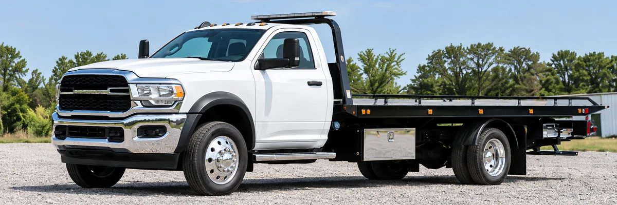 Illustrative white rollback tow truck with a flat carrier bed